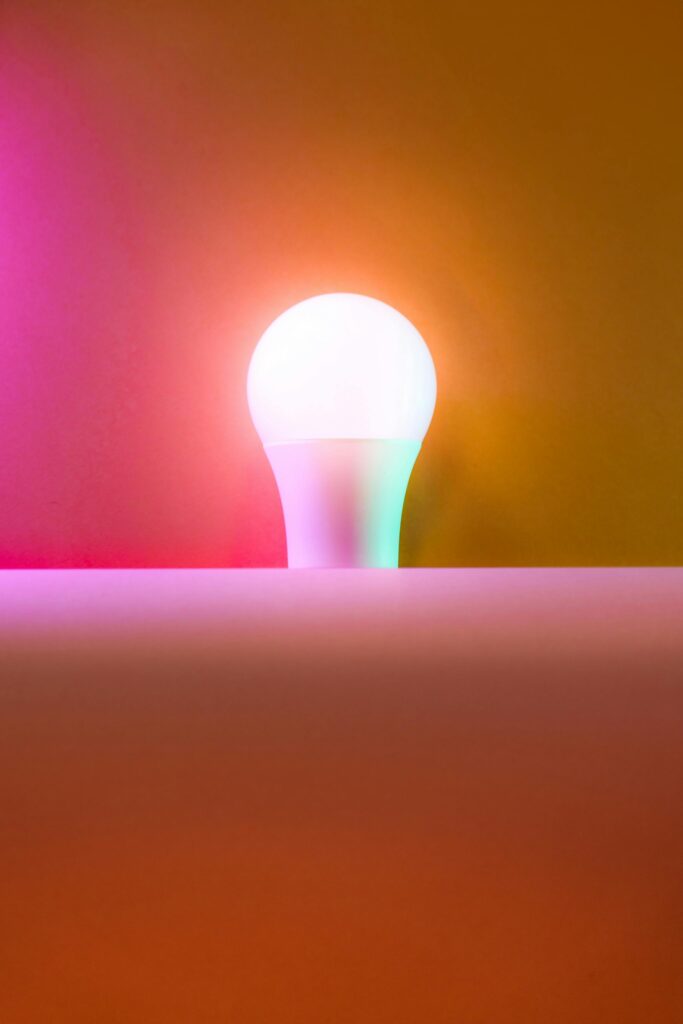 Vibrant light bulb glowing with multicolored hues on a gradient backdrop, offering creative inspiration.